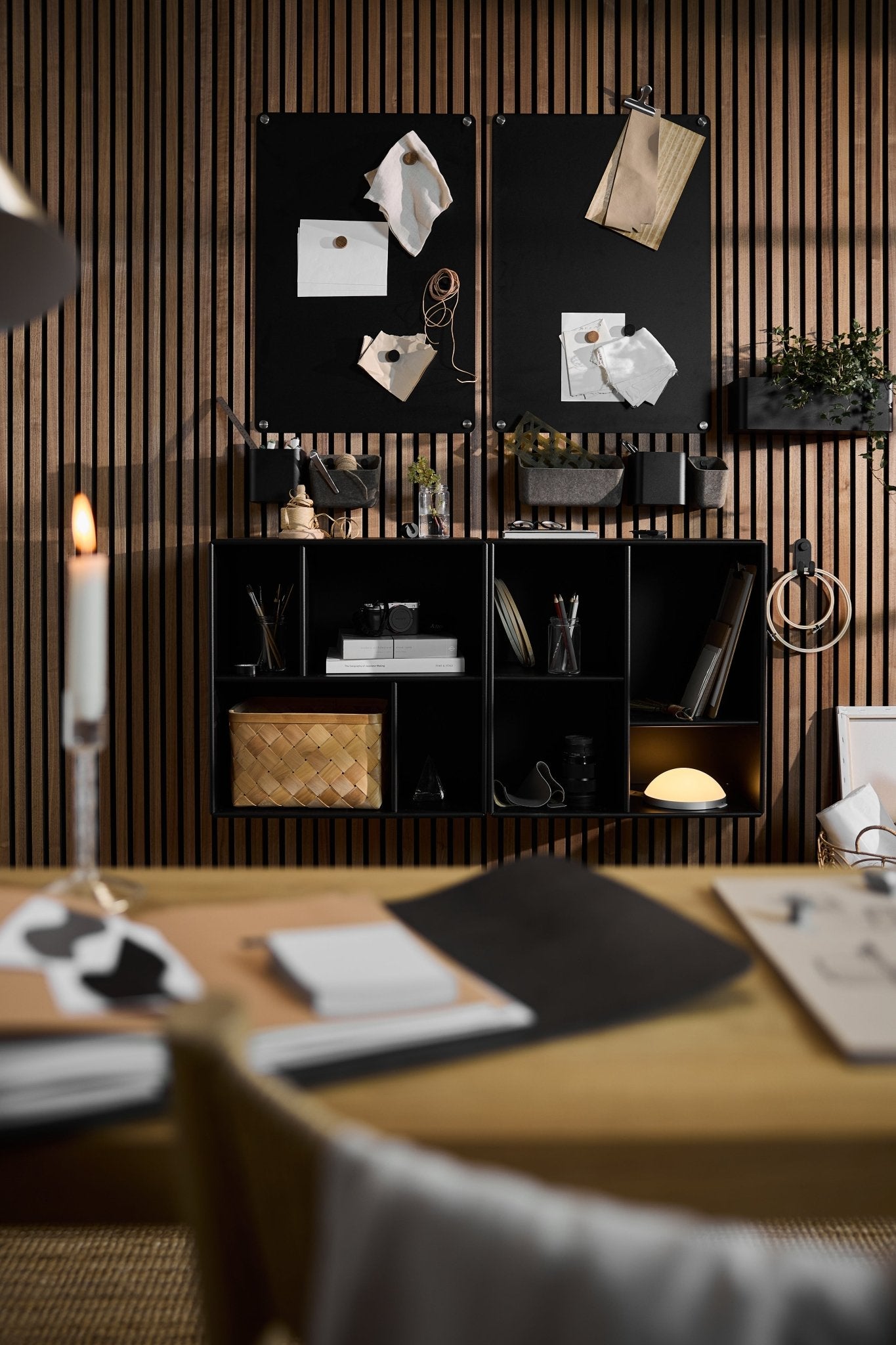 Spazio di lavoro moderno arredato con mobili in stile nordico, una parete acustica in doghe di legno Akupanel, una vetrina aperta WoodUpp Arka con ripiani neri, bacheche e articoli per la scrivania.